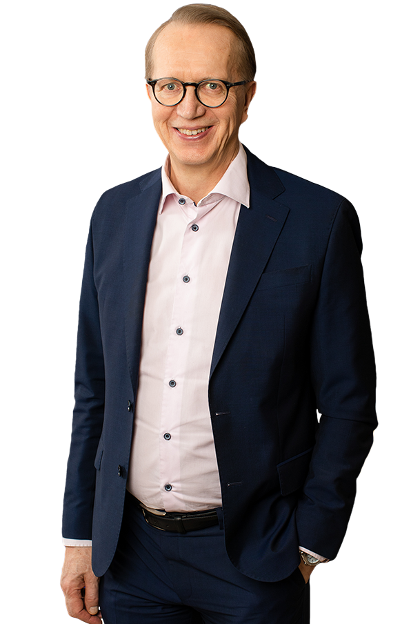 Janne Metsämäki har jackan öppen på sin börka kostym. Han ser i kameran och har ett leende om ansktet.